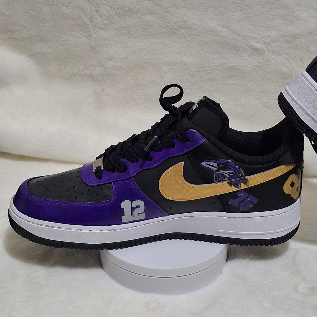 Close-up of custom sports-themed Nike Air Force 1 sneakers in purple, gold and black side view