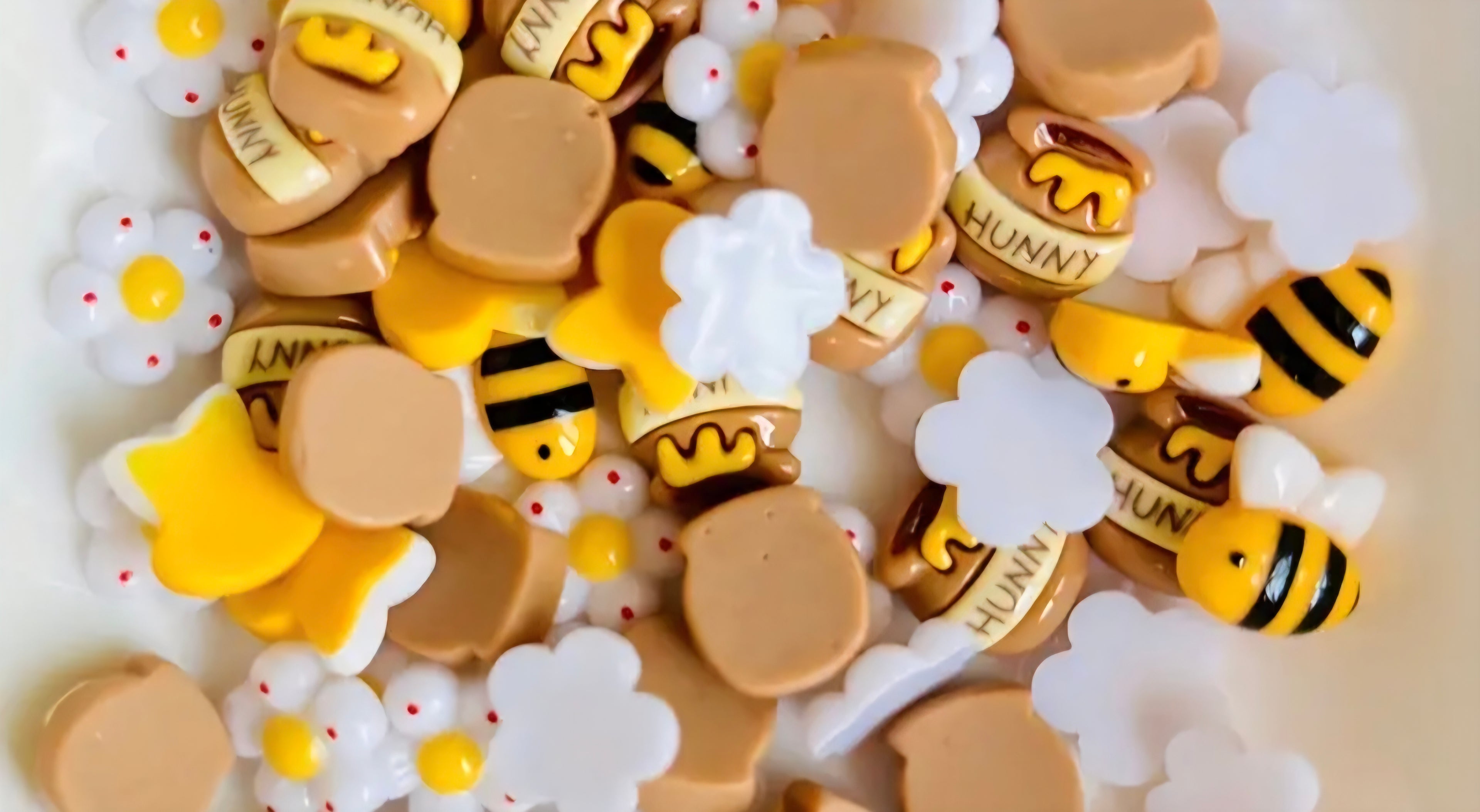 Decorative craft charms including bees, flowers, and a crown with 'Honey' text on a white background.