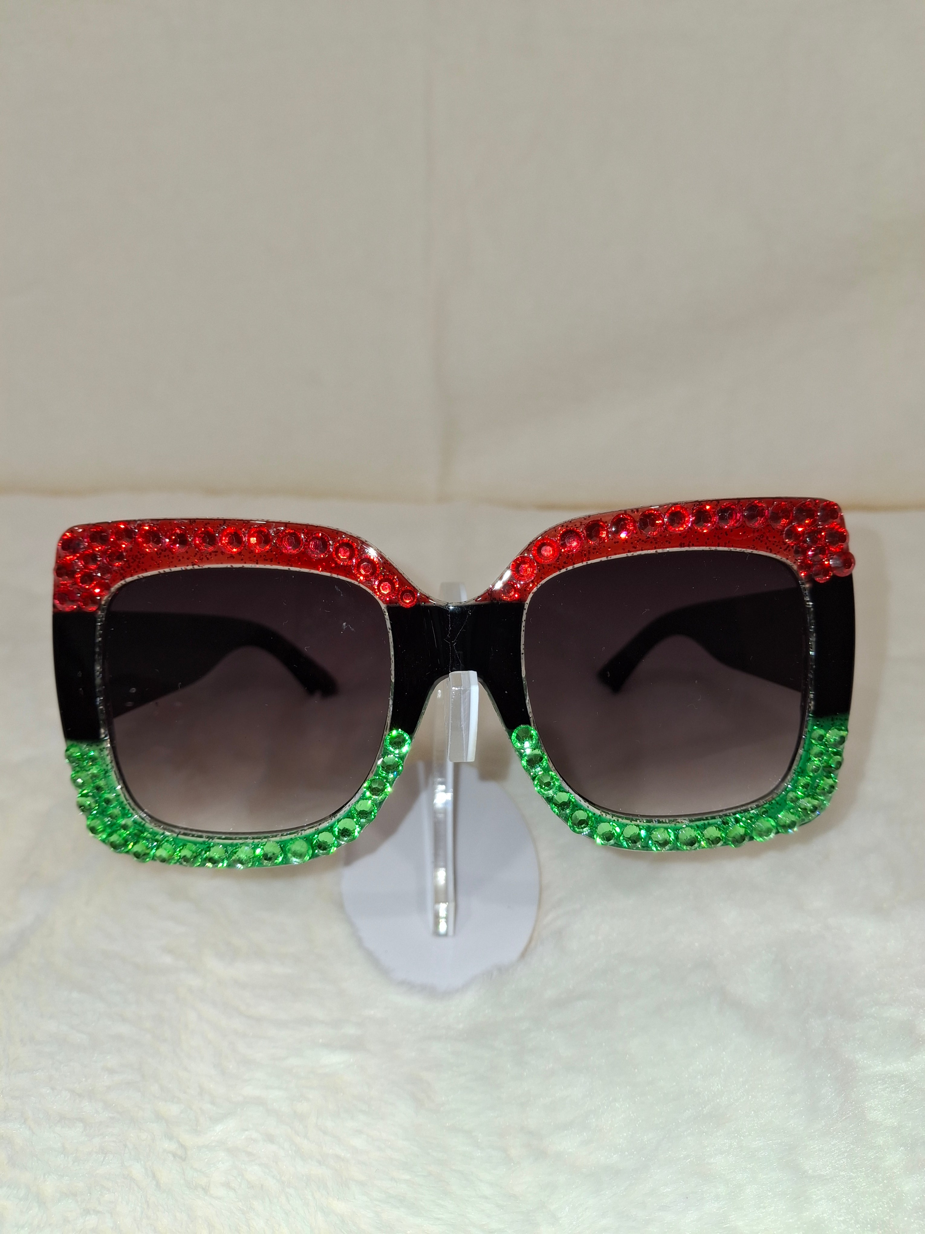 Sunglasses with colorful red. green and gold gemstones on a white background