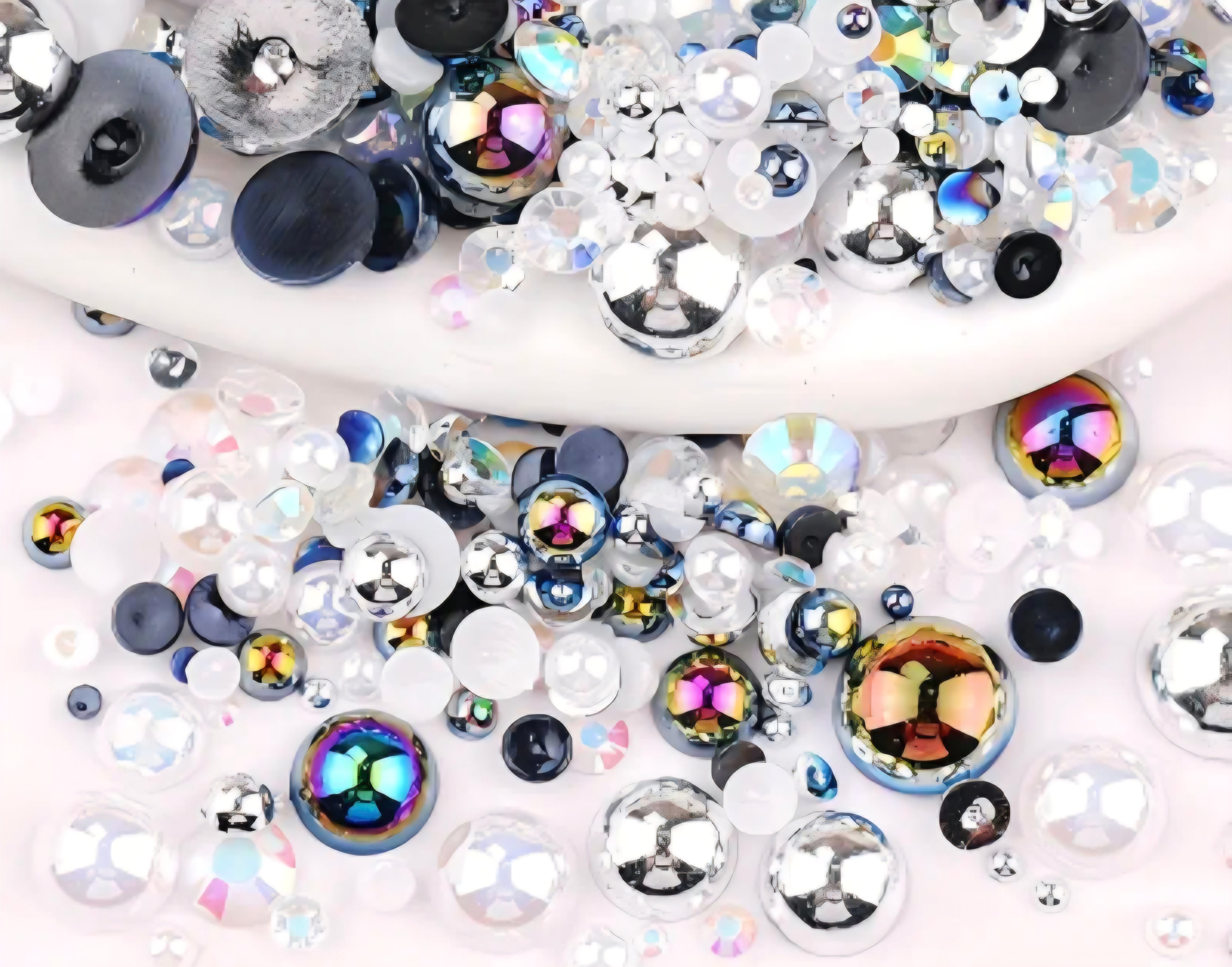 Assorted black white and silver gemstones and rhinestones on a white background
