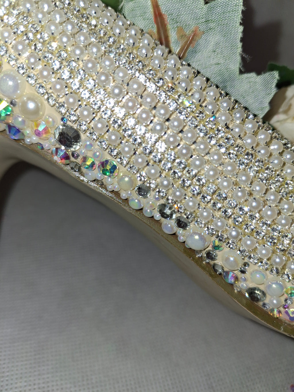 Close-up of a shoe with pearl and crystal embellishments on a neutral background