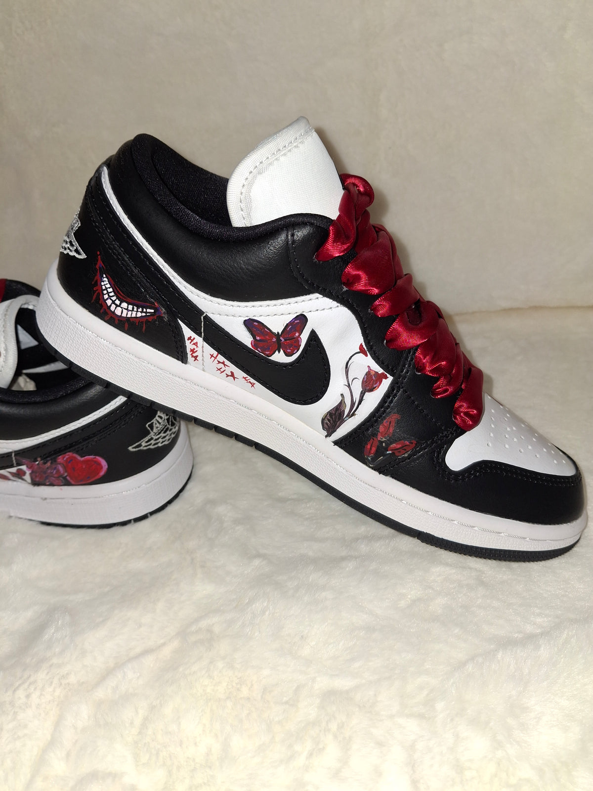 Black and white Jordan sneakers with red laces and red hand painted butterflies and flowers. 