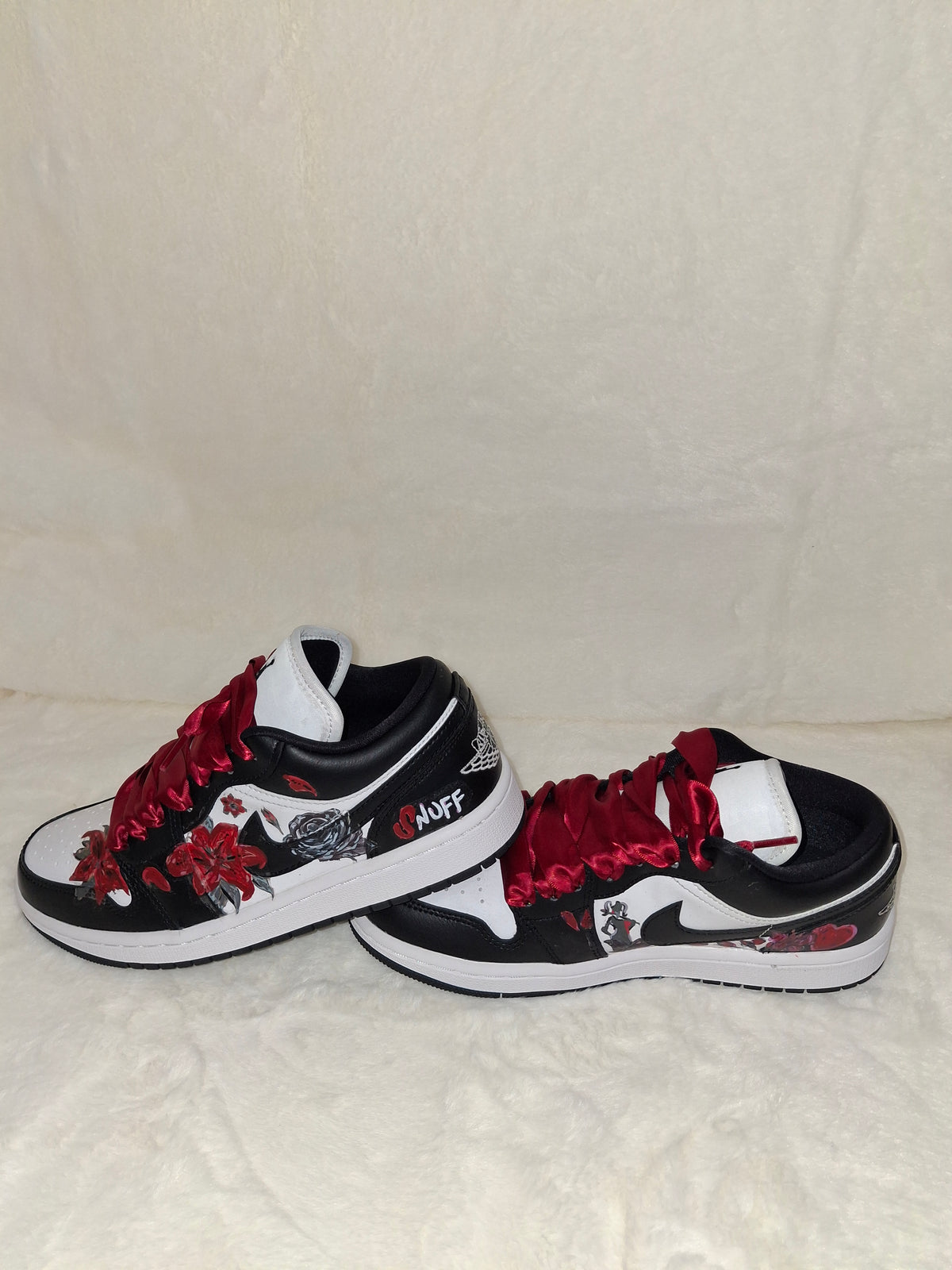 A pair of custom Nike sneakers in black, white, and red, featuring red roses and red laces