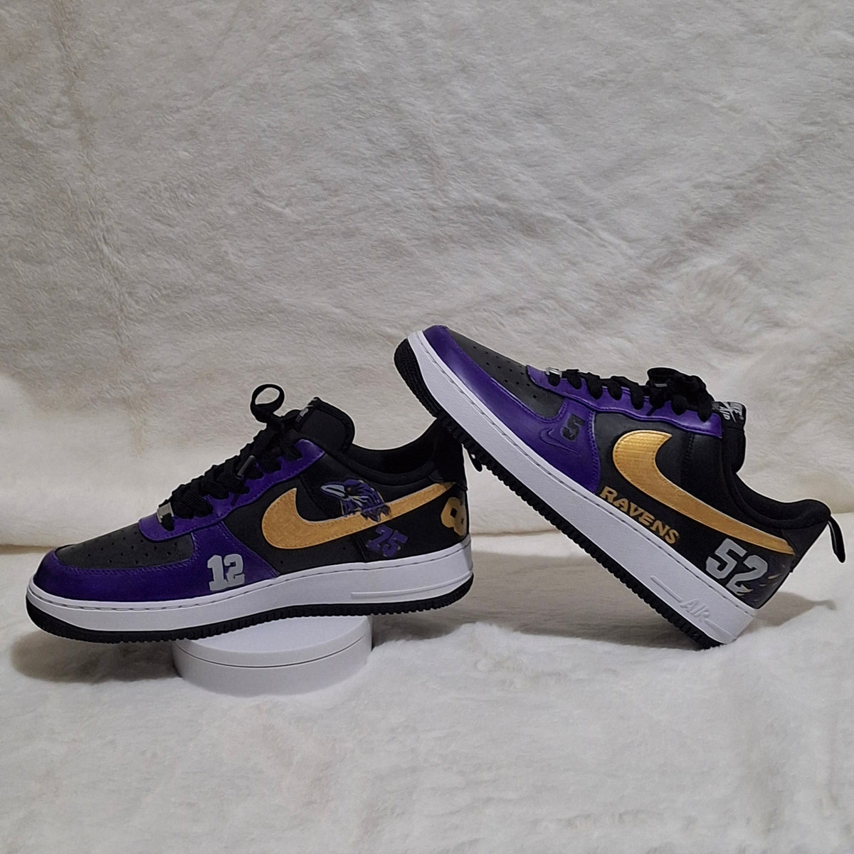 Custom hand-painted Nike Air Force 1 sneakers showing contrasting purple and gold design and sports inspired theme. 