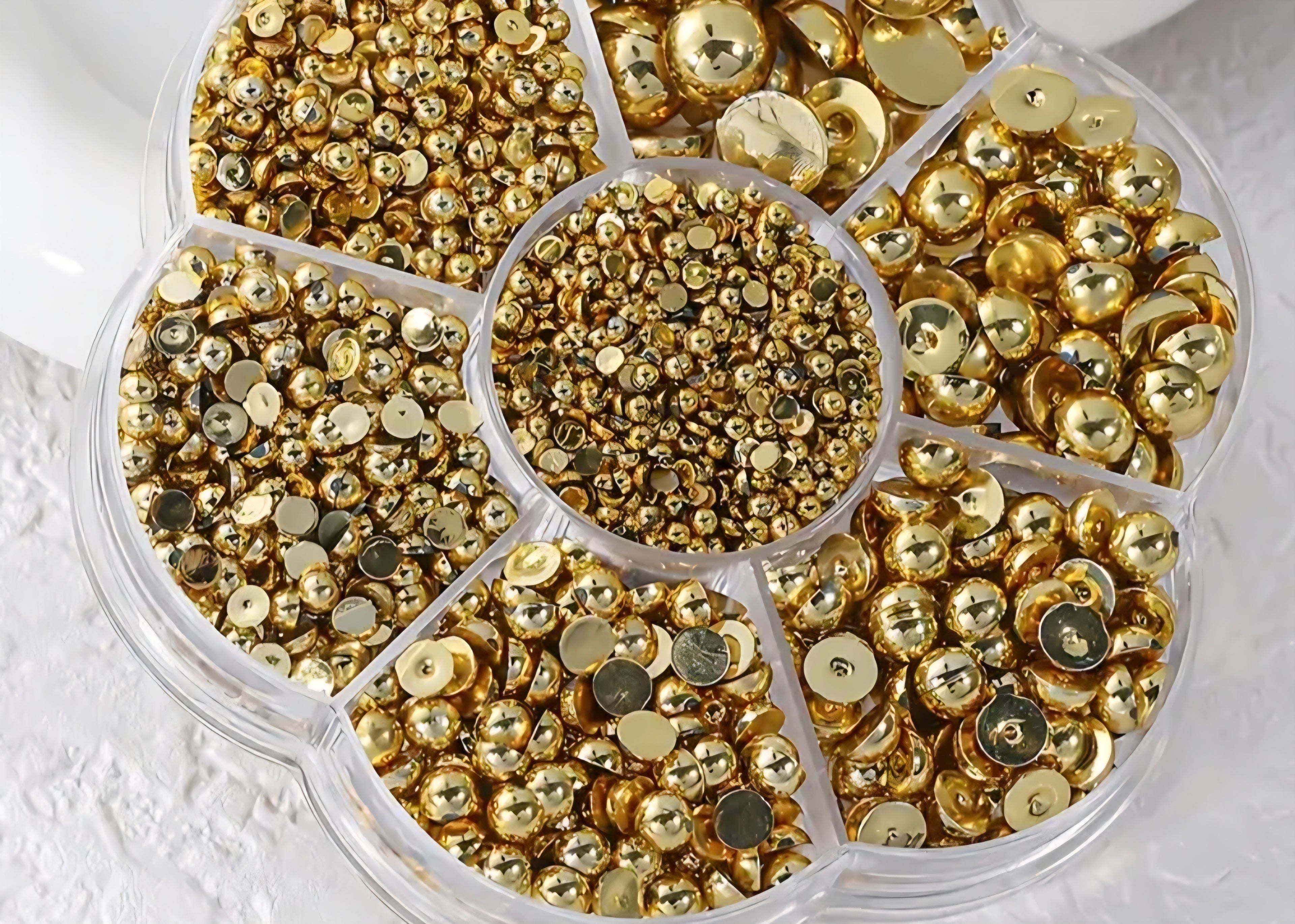 Gold pearls for crafts and nail art on a white background