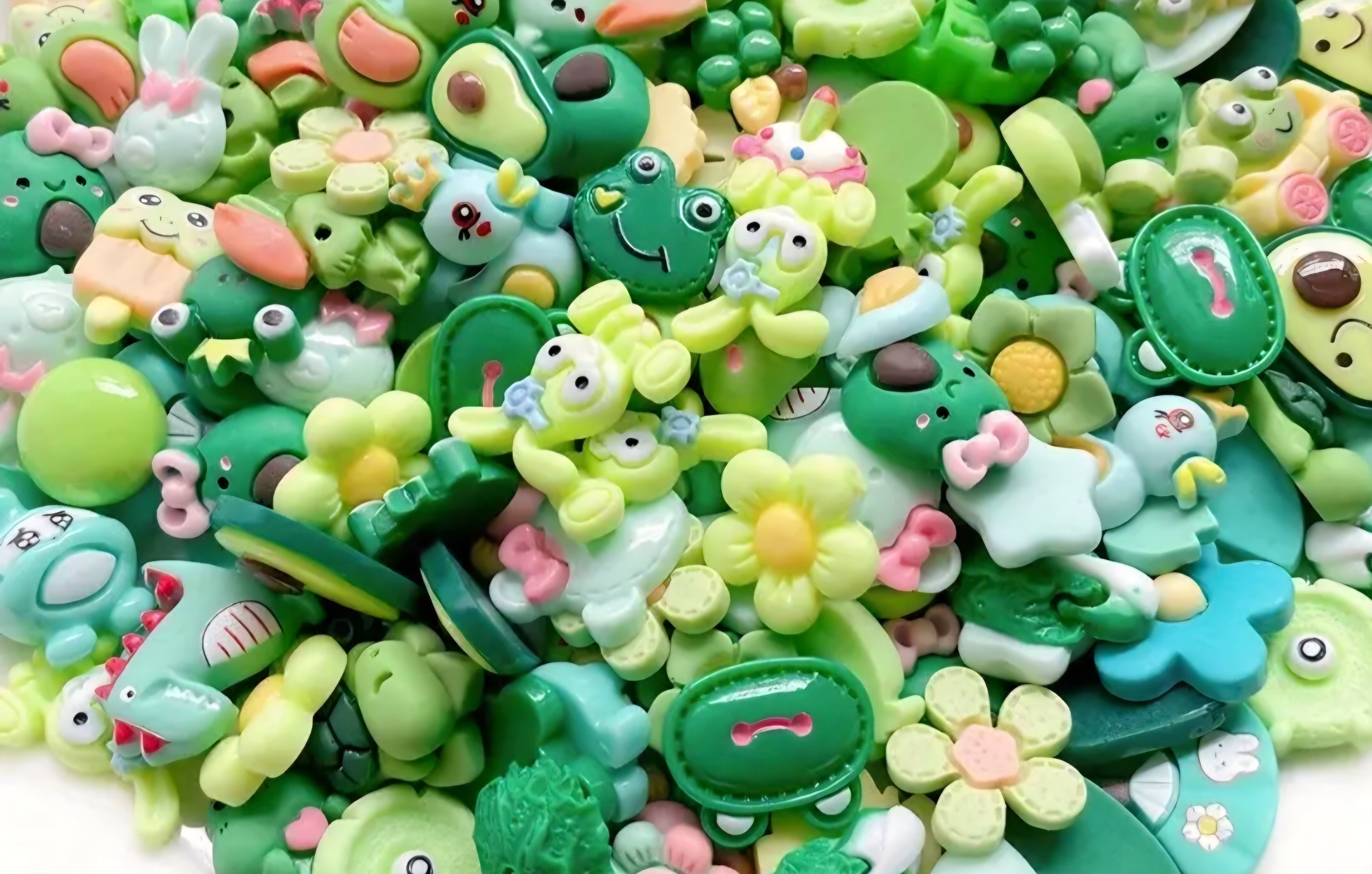 Assorted green charms with cartoon designs on a white background