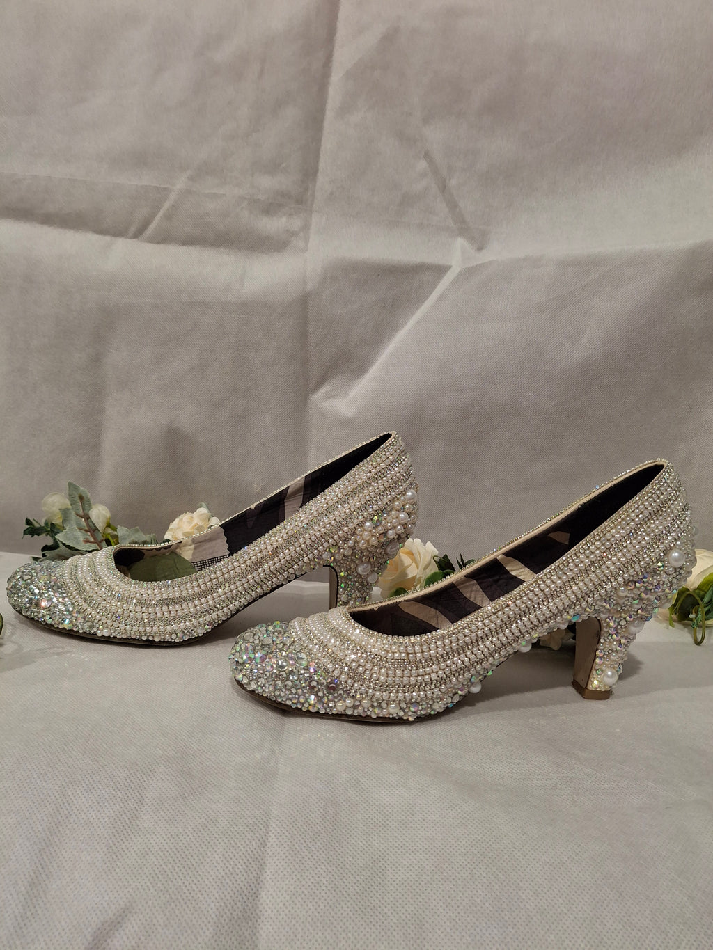 Pair of embellished high-heeled shoes on a light gray background