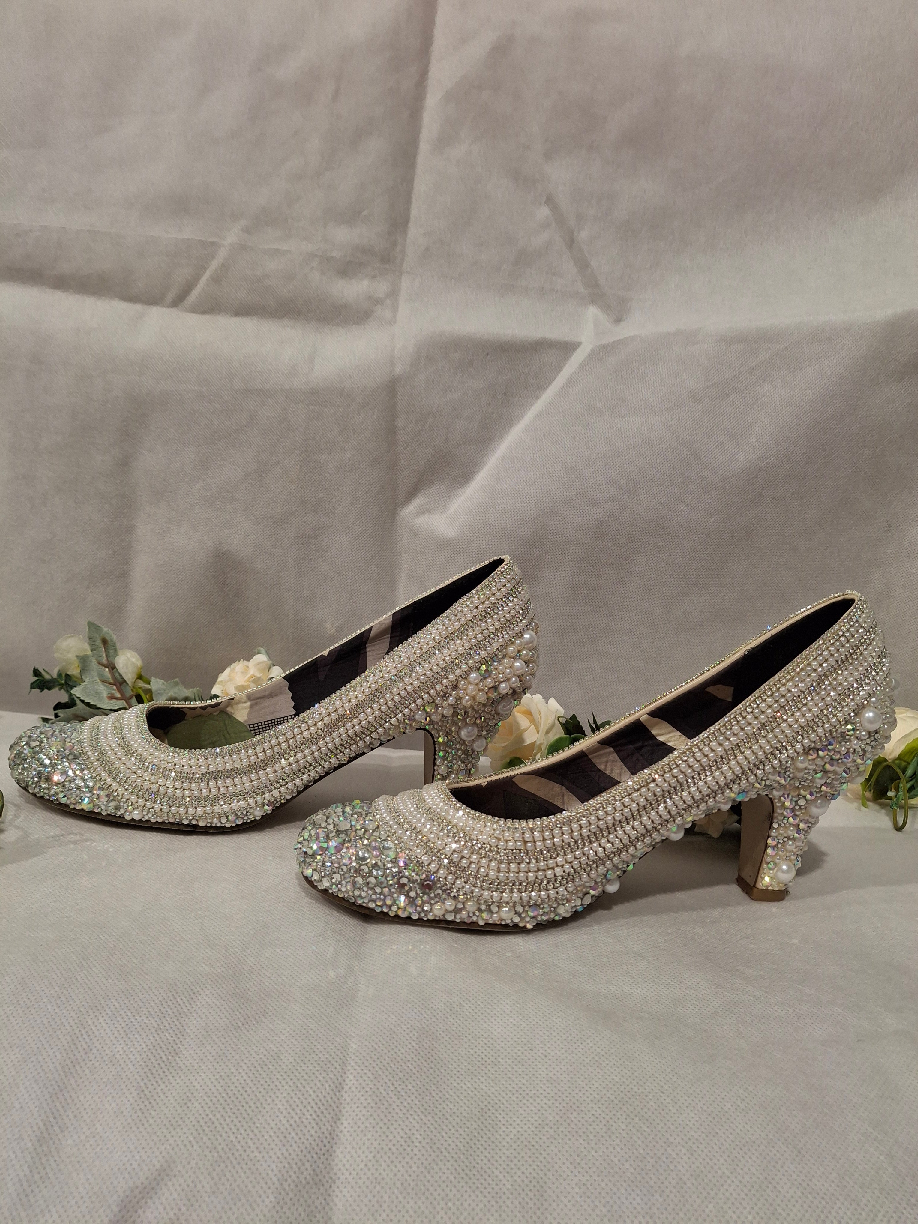 Pair of embellished high-heeled shoes on a light gray background