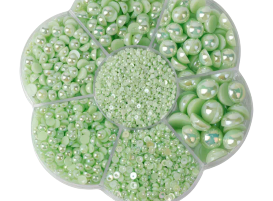 Green pearl assortment in a circular container on a white background