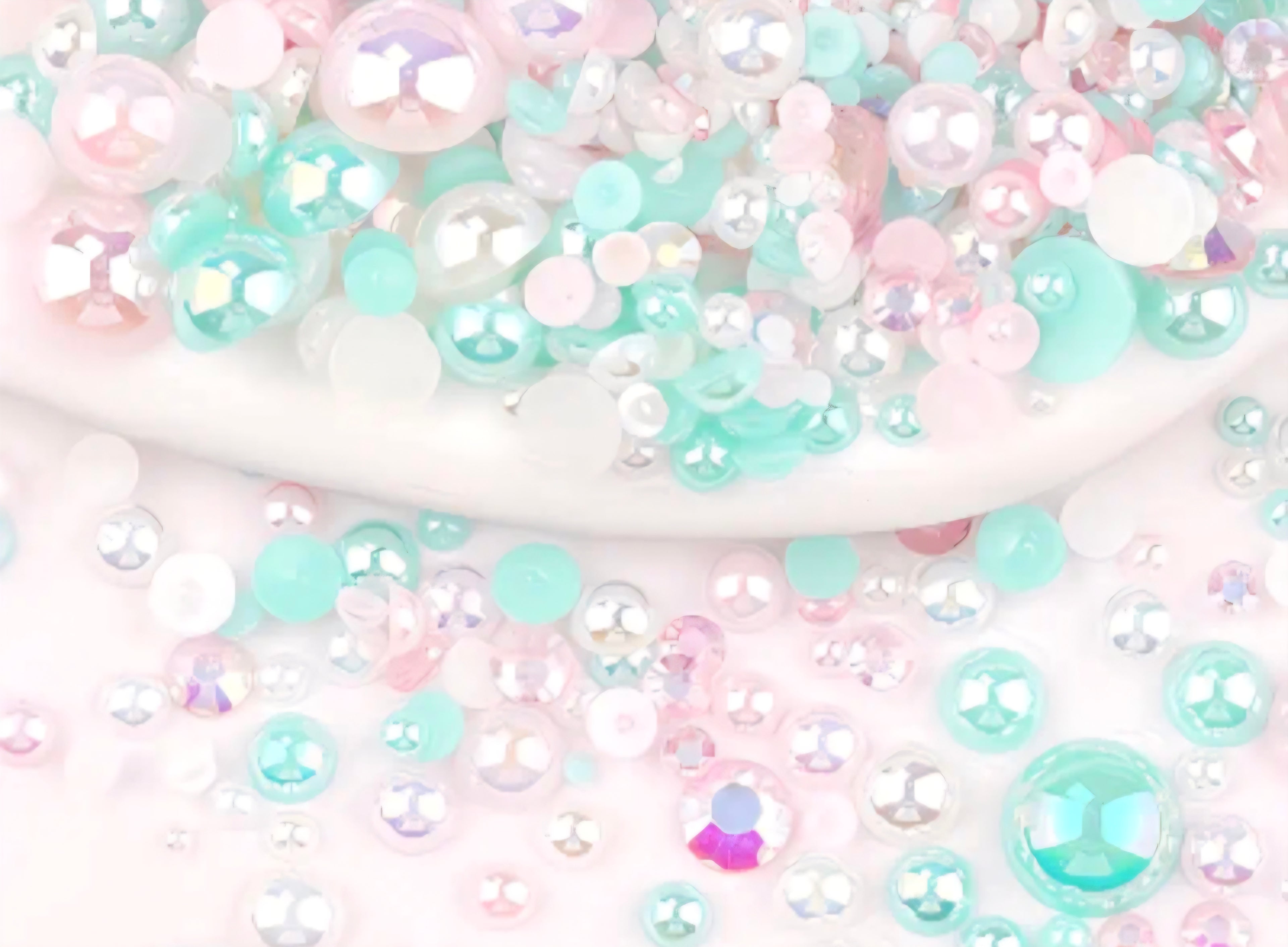 Pastel-colored rhinestones and pearls on  white background