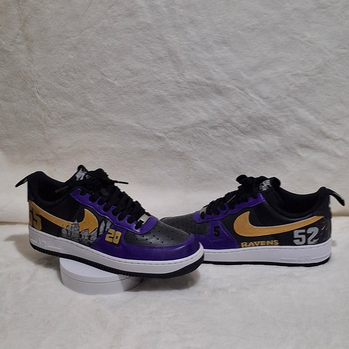 Side by side view of personalized Nike Air Force 1 sneakers with purple, gold and black accents and sports inspired detailing. 