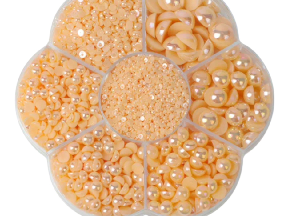 Assorted size champagne colored Pearls in a plastic organizer on a white background