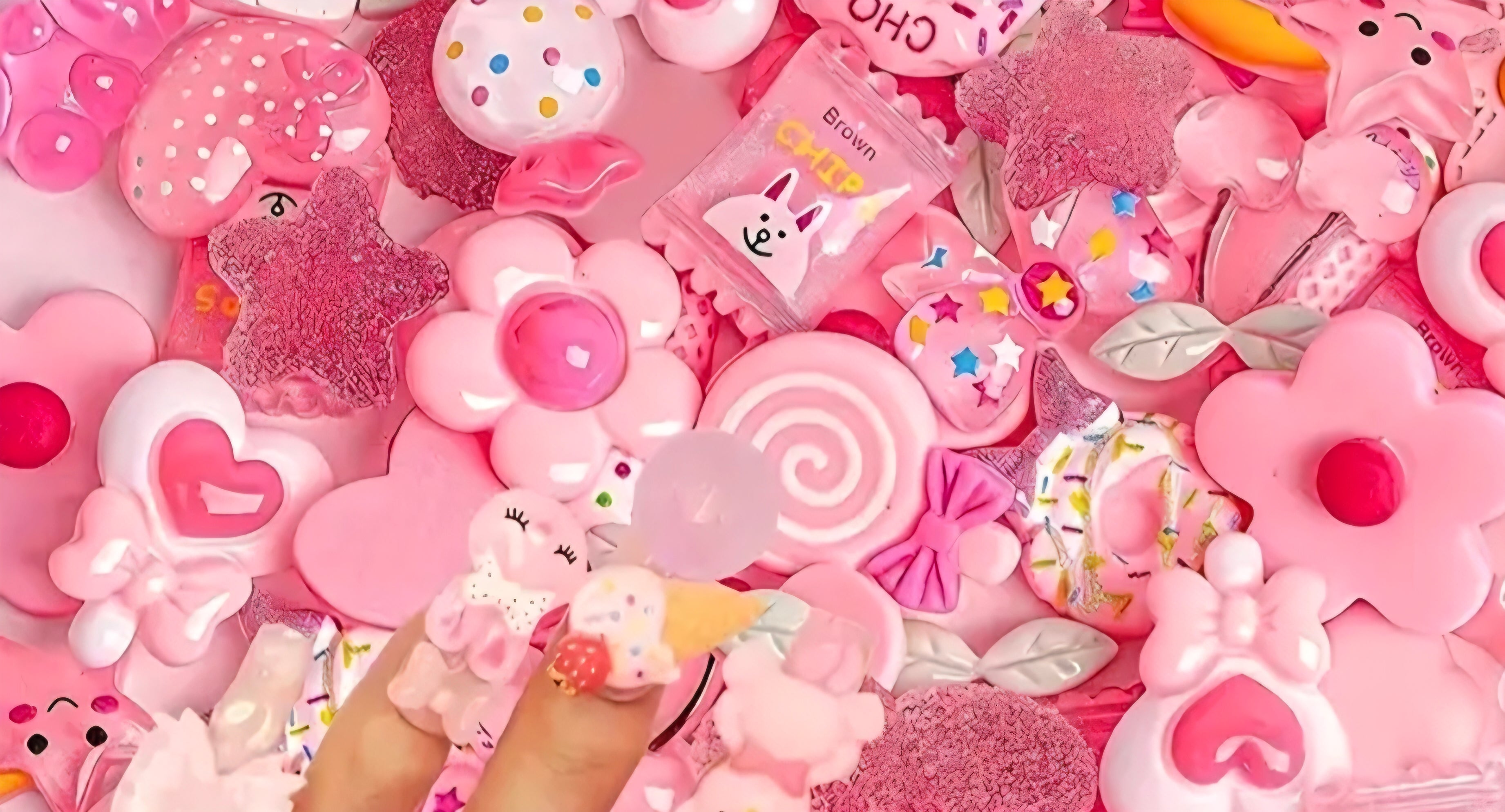 Collection of pink decorative charms including flowers, hearts, and candy shapes.