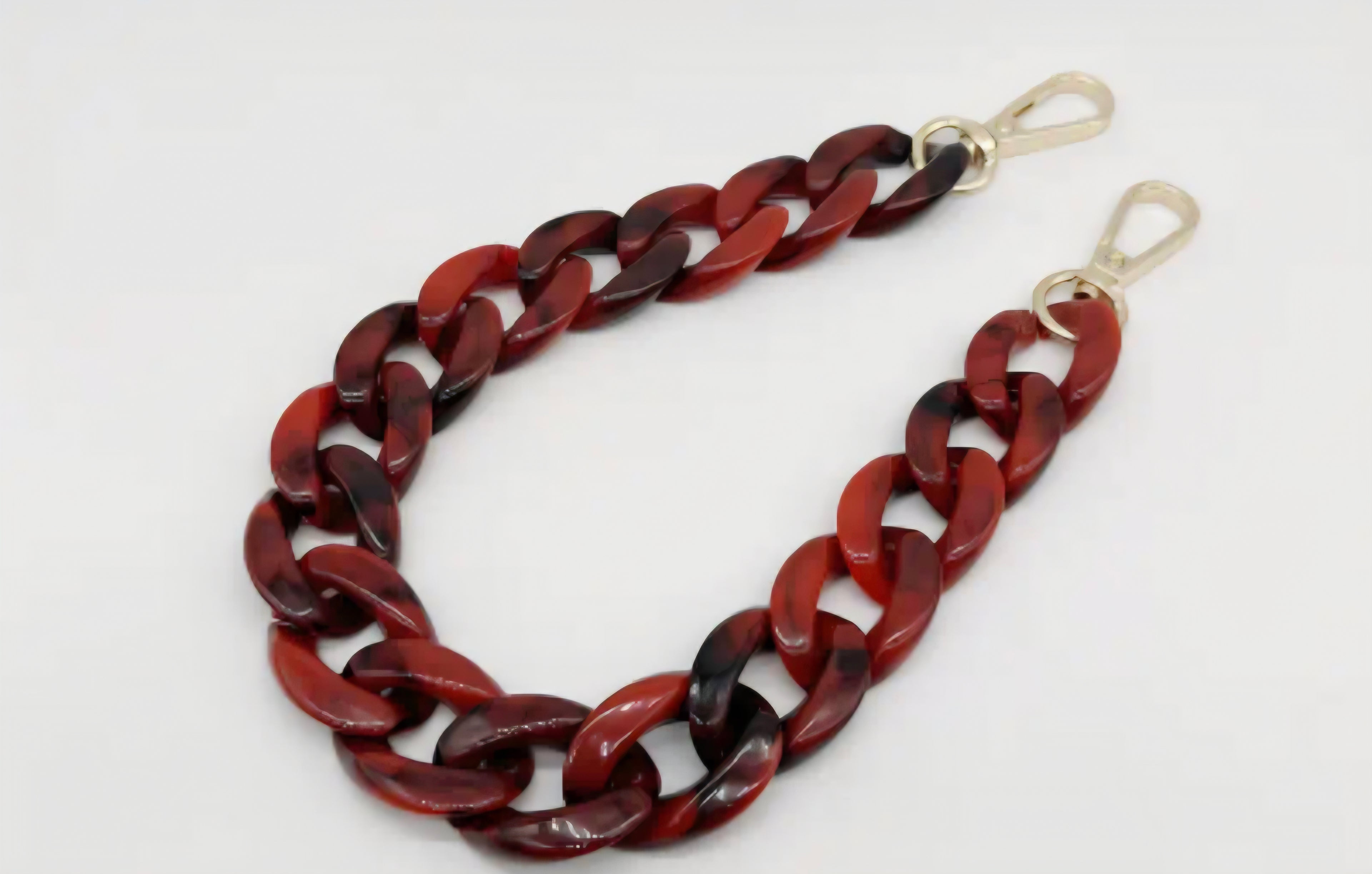 Red and black chain bag strap on a white background