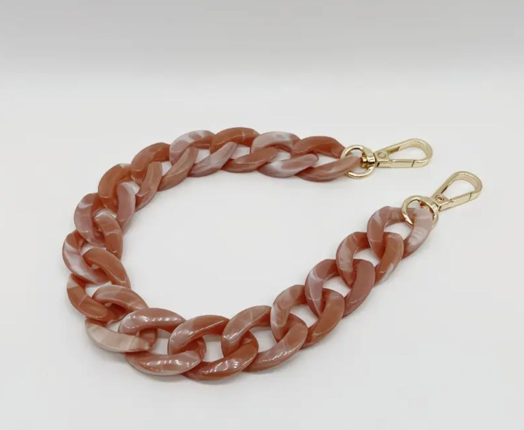Pink chain bag strap with gold hardware on a white background