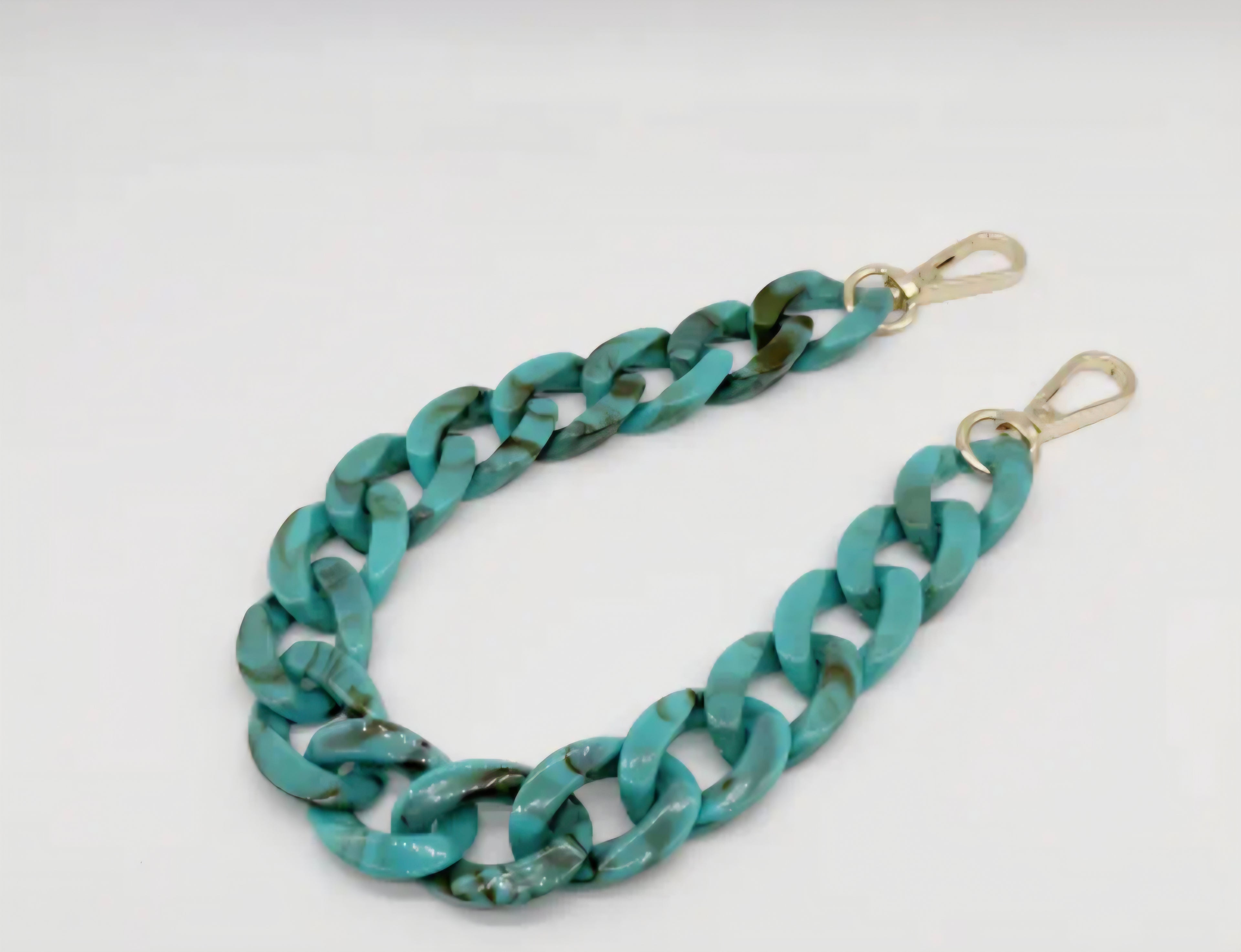 Turquoise chain strap with gold hardware on a white background