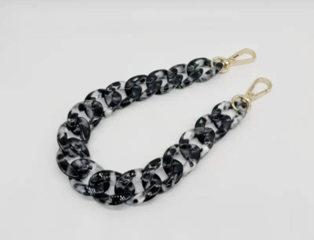 Black and white patterned strap with gold clasp on a light gray background
