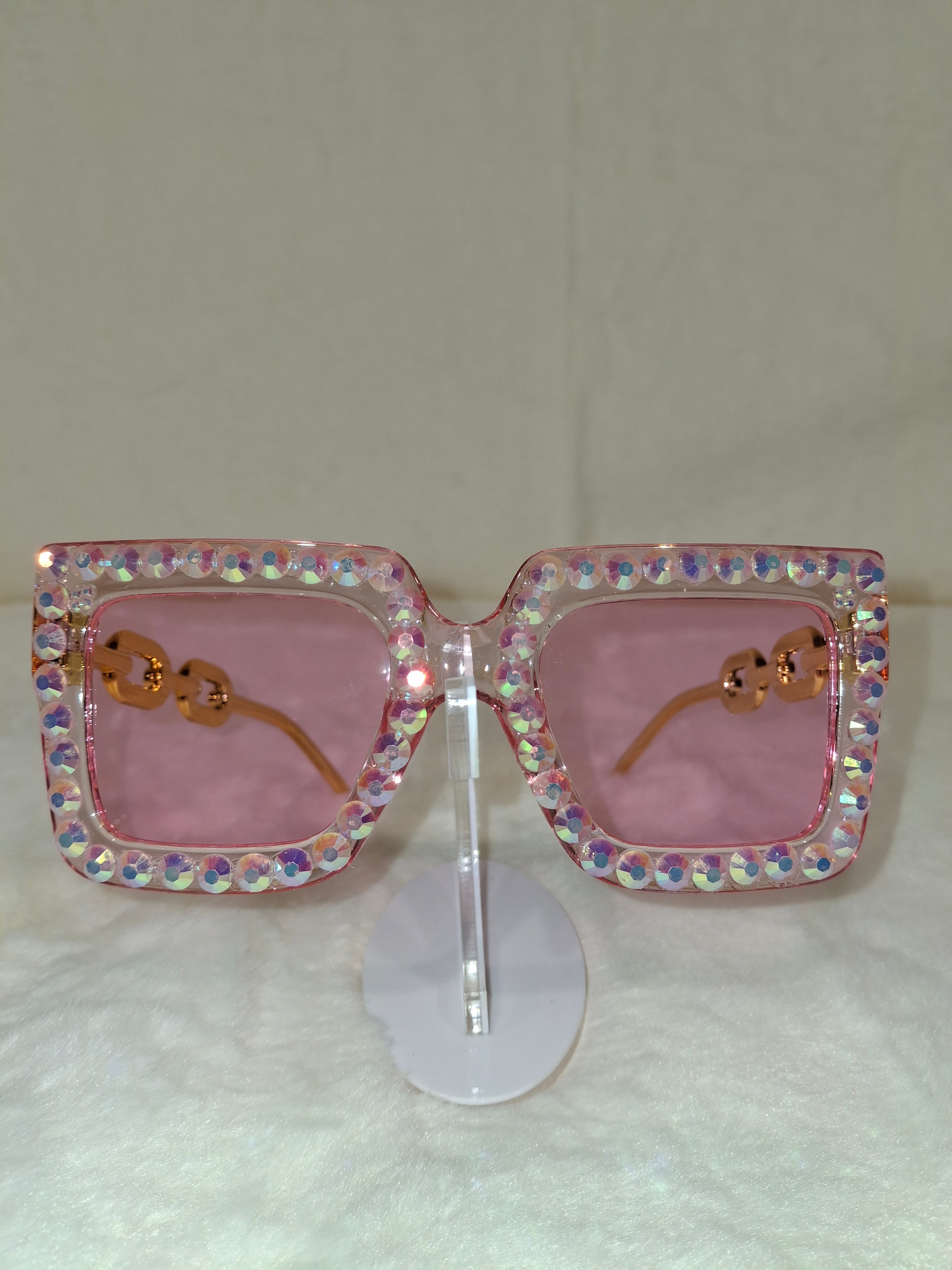 Sunglasses with a rhinestone frame and pink lenses on a white background