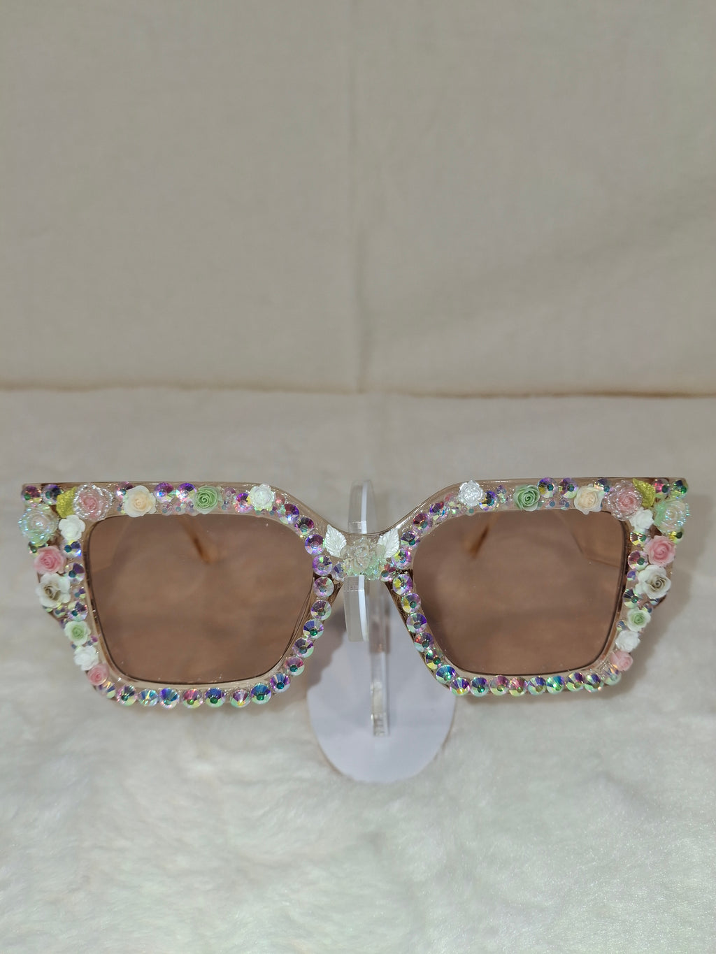 Sunglasses with colorful gemstone embellishments on a beige background