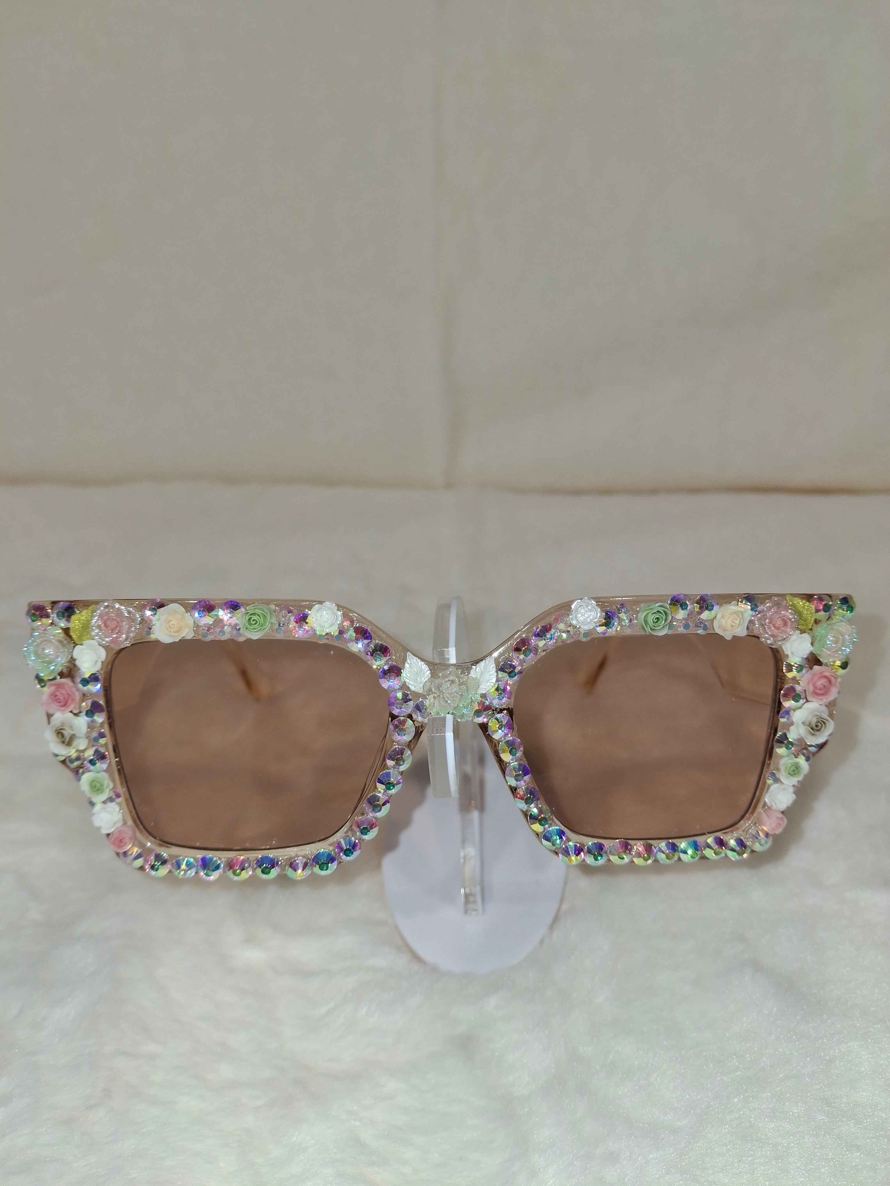Sunglasses with colorful gemstone embellishments on a beige background