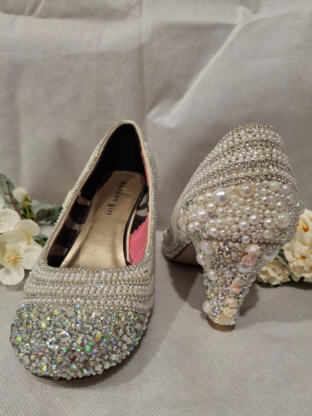 Sparkly high-heeled shoes with rhinestones and pearls on a light background