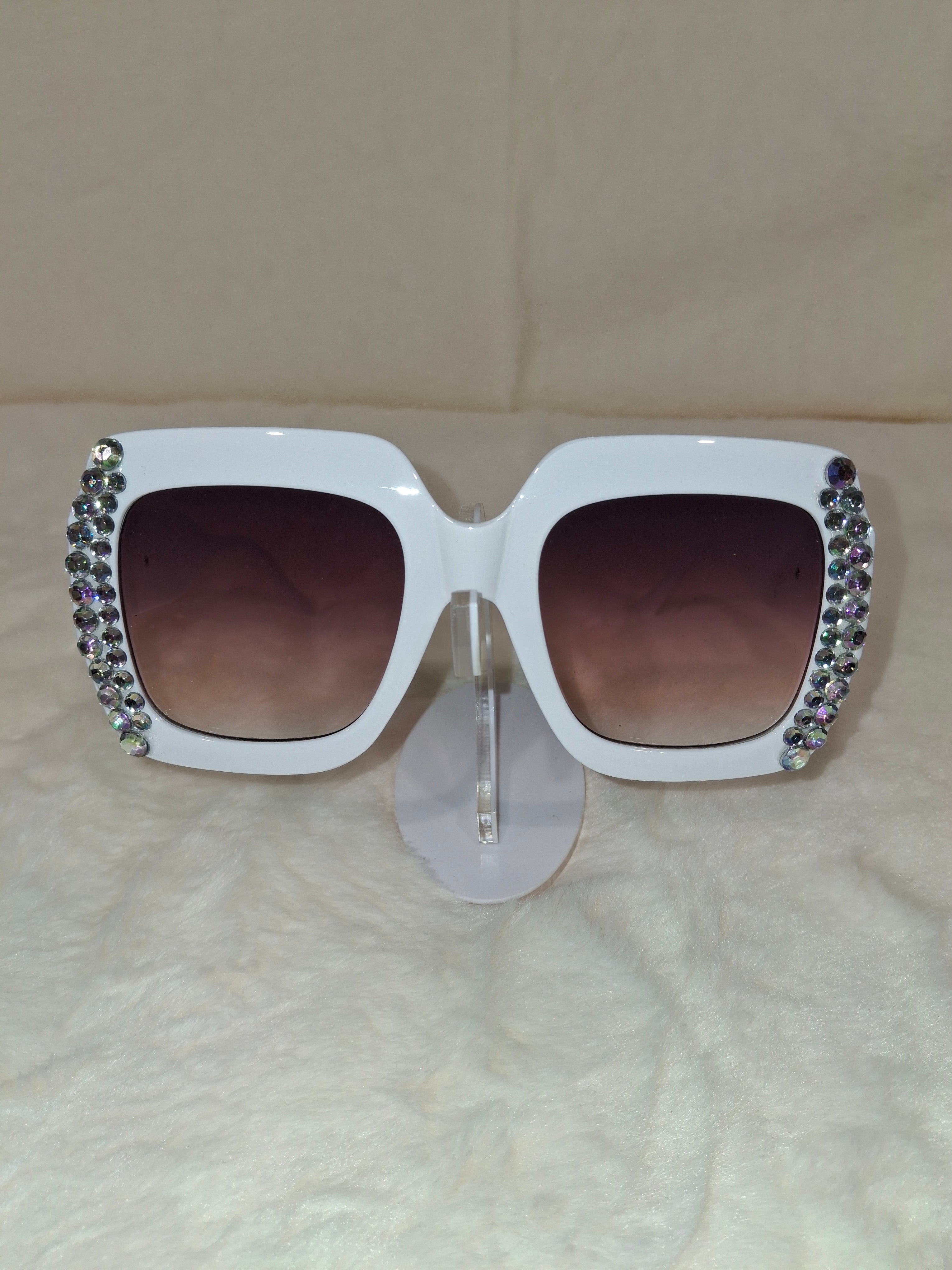 White sunglasses with rhinestoneson a beige background