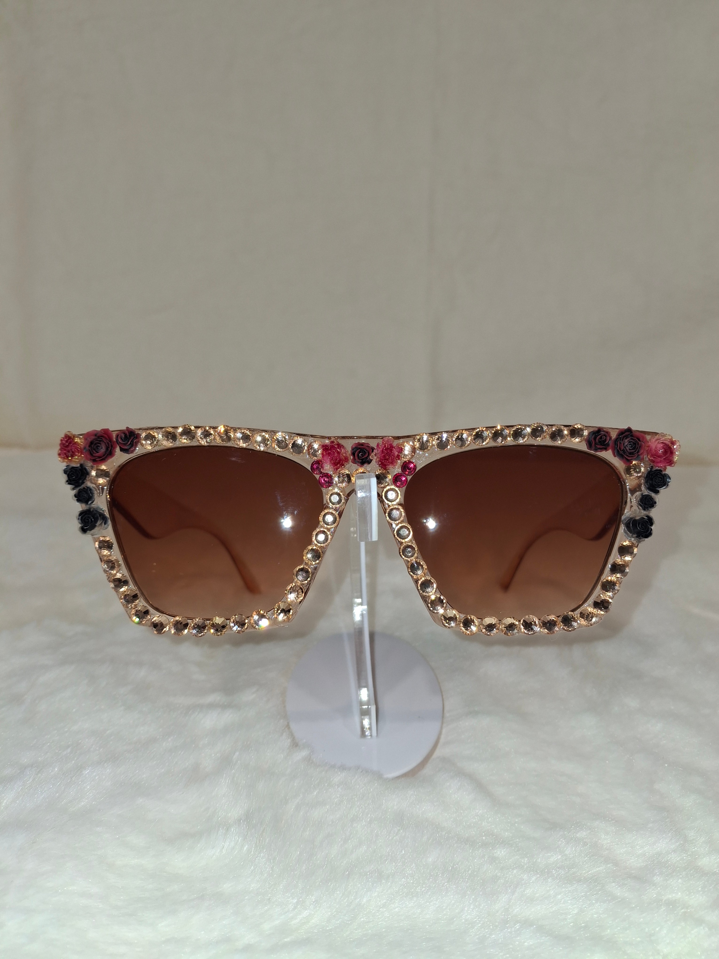 Sunglasses with rhinestone and flower embellishments on a white background