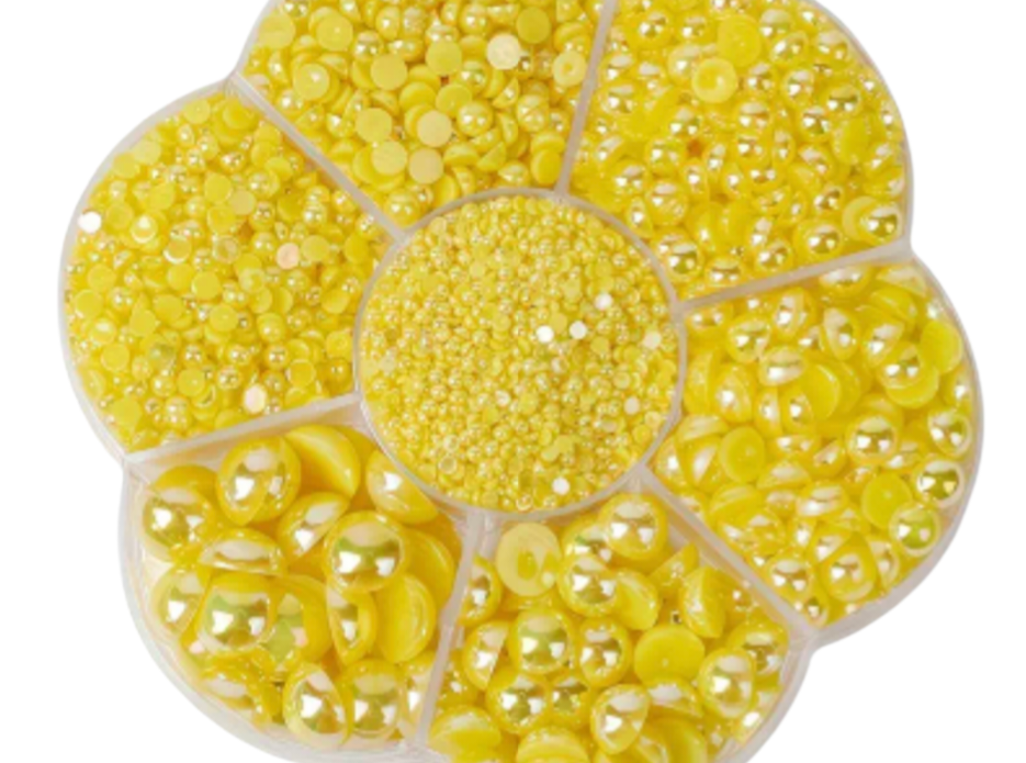 Round container with yellow pearls of different sizes on a white background